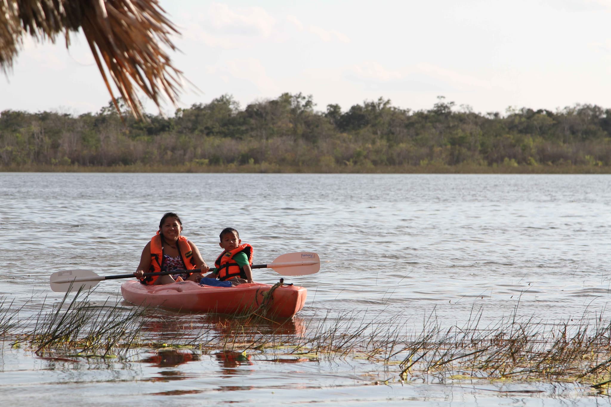 A mother and child paddling a kayak on a lagoon in Maya Ka'an