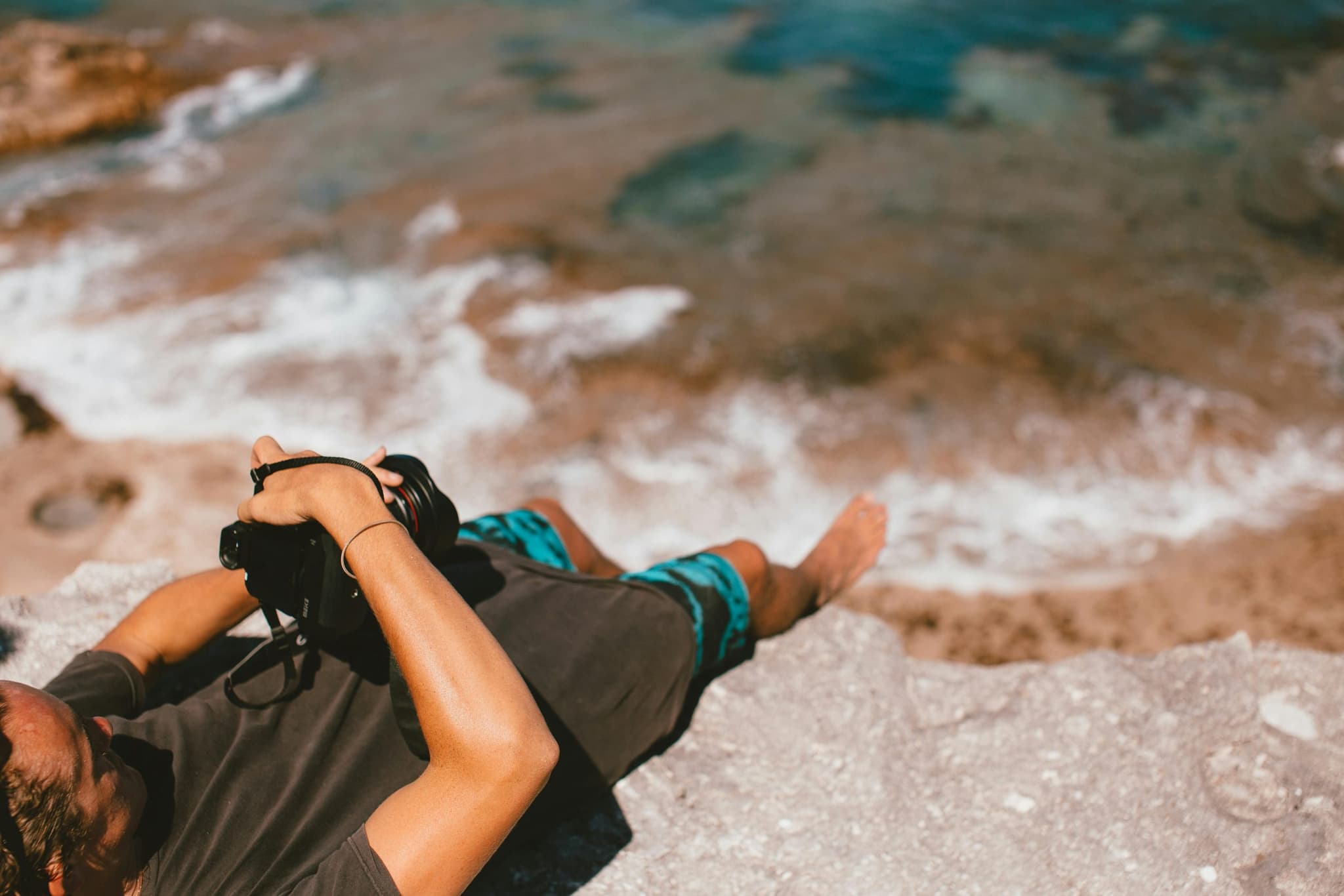 Photographer lying on the rock, shooting out to sea