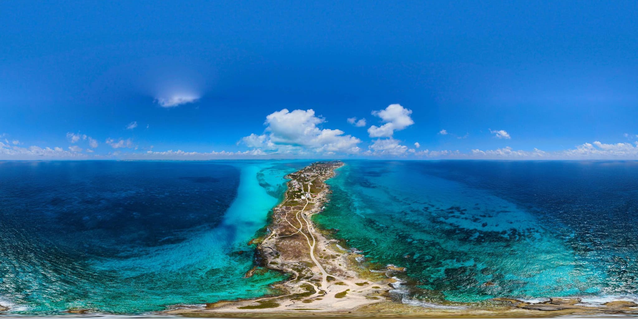Aerial view of Isla Mujeres between the deep blue sea and the turquoise water along its shore