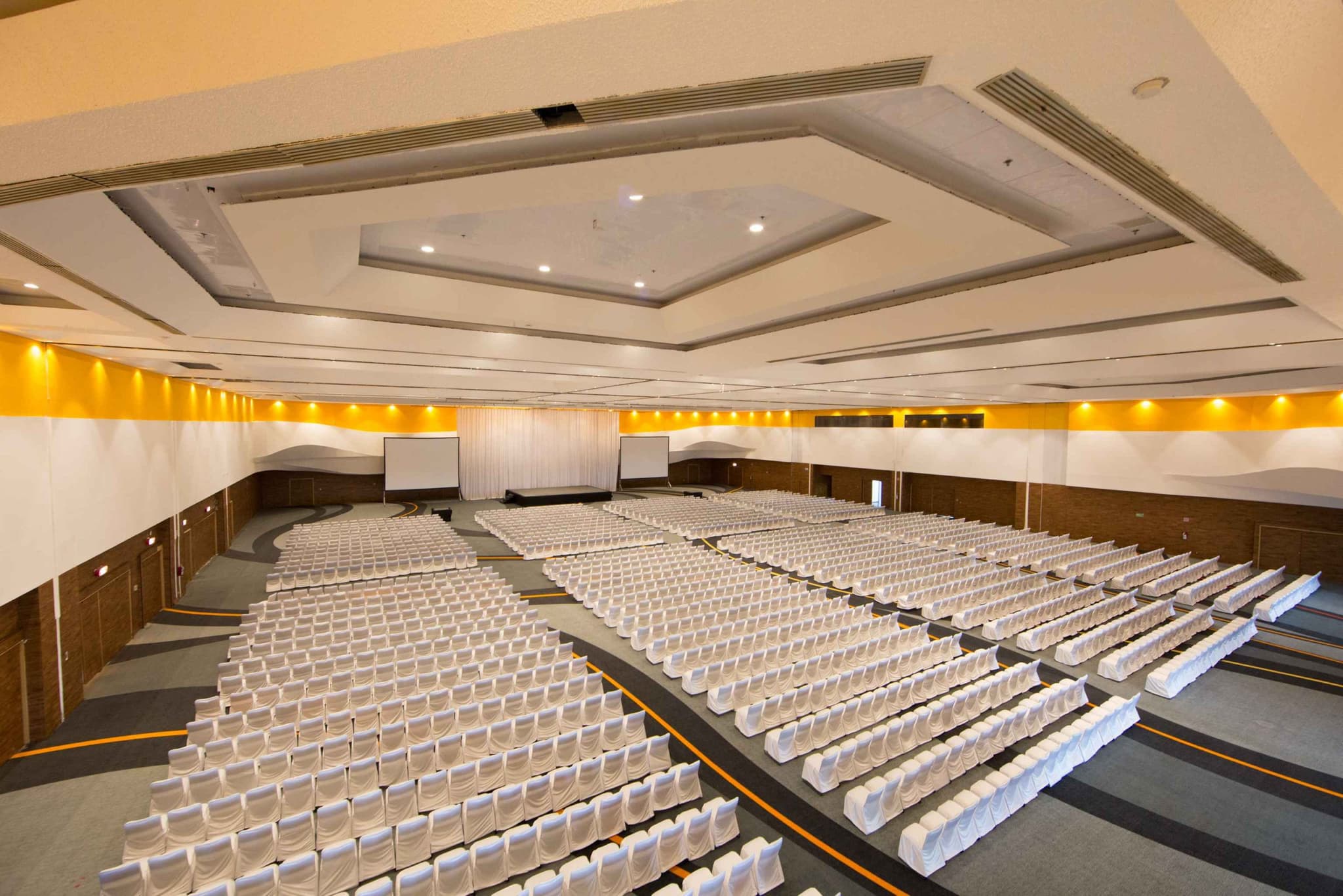 An auditorium set with rows of white-dressed chairs