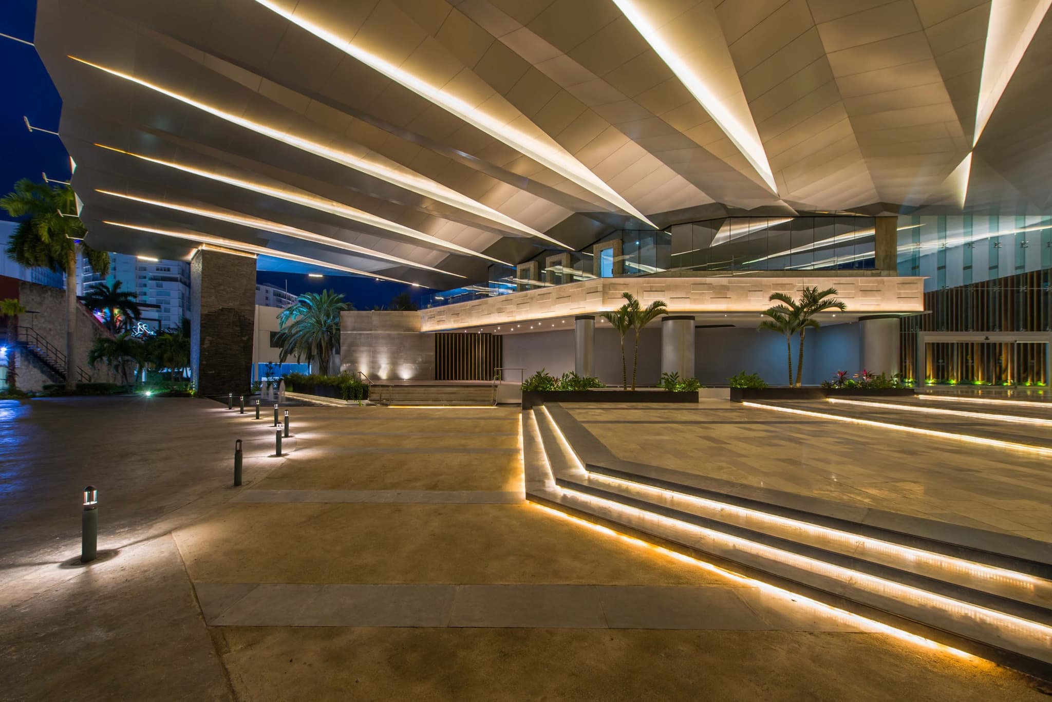 The lit forecourt of the Cancún convention centre at dusk