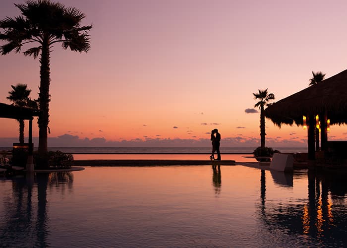 Couple embracing at sunset beside a pool facing the Caribbean