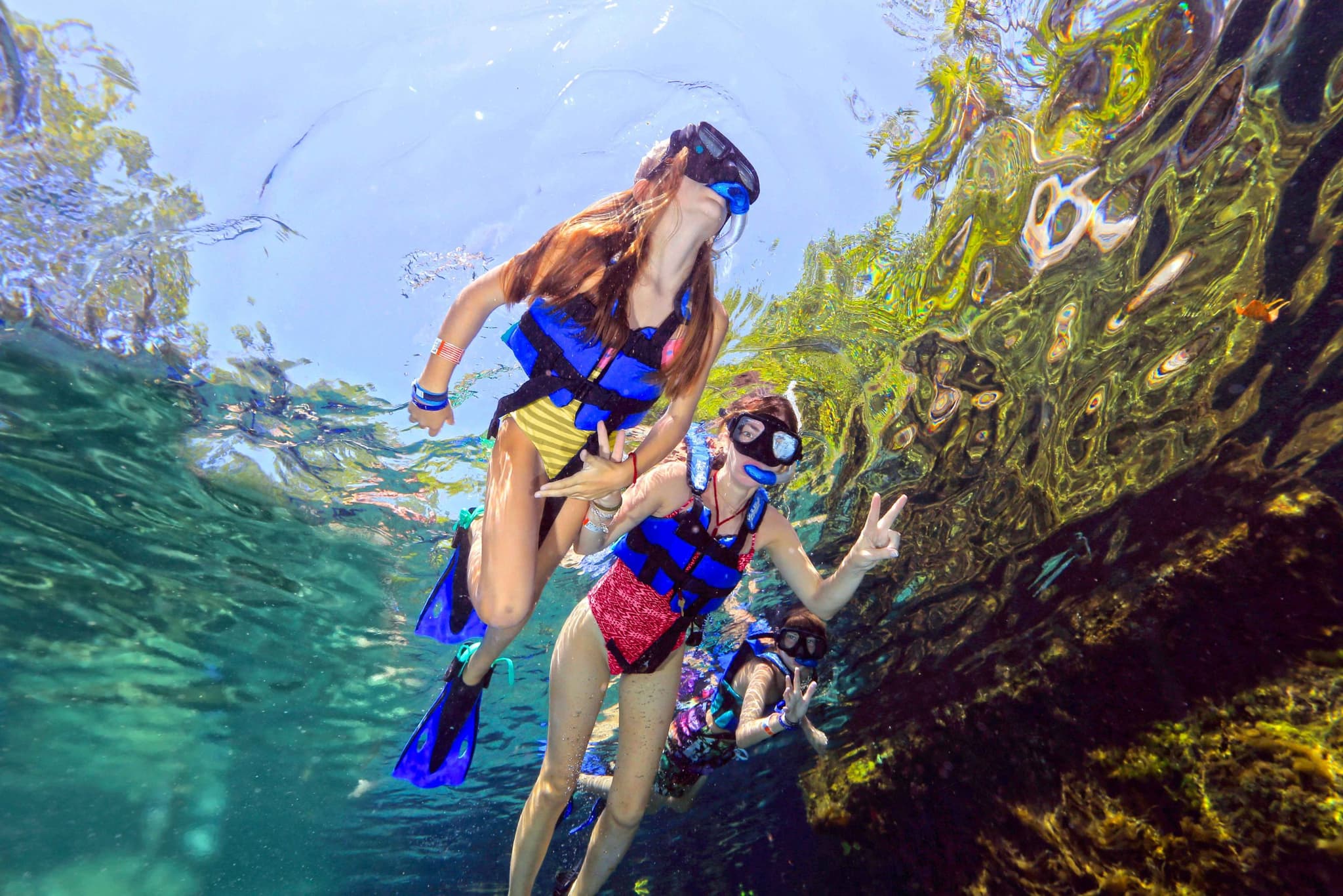 Three girls snorkelling over a shallow reef
