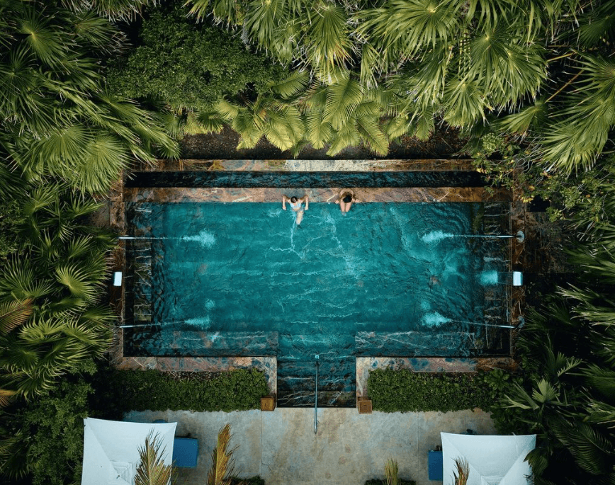 Stone pool seen from above, ringed by palms