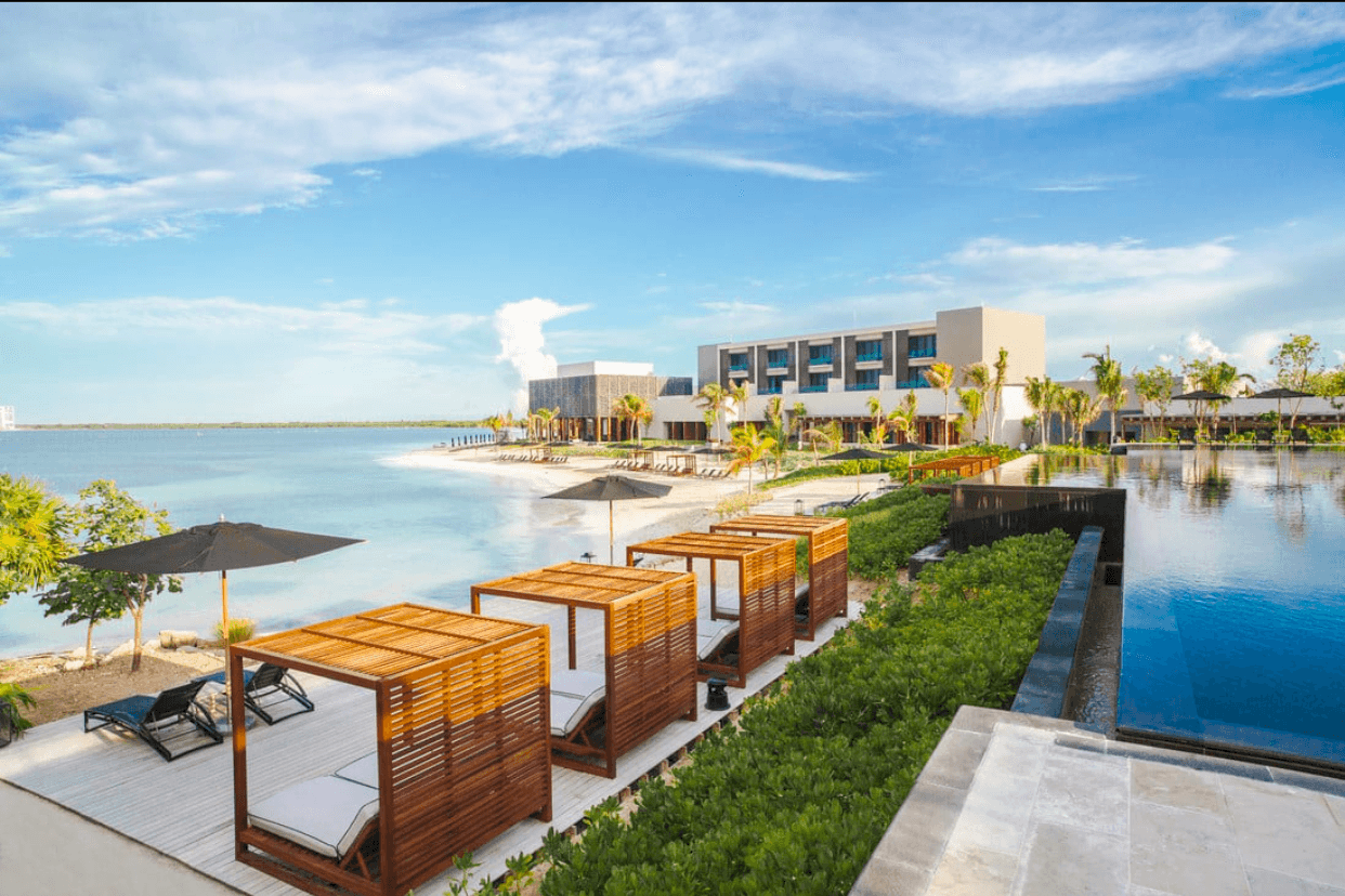 Wooden daybeds by the pool, the beach and the lagoon beyond