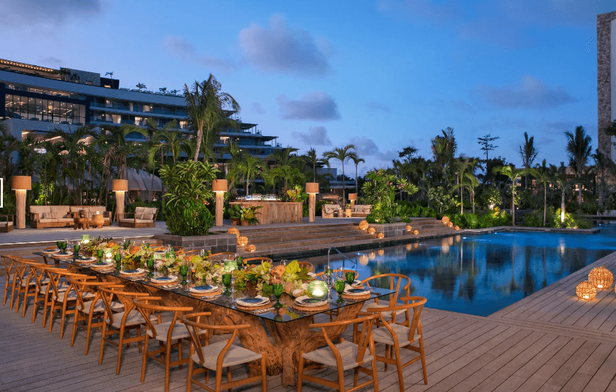 A long table set beside the pool at dusk