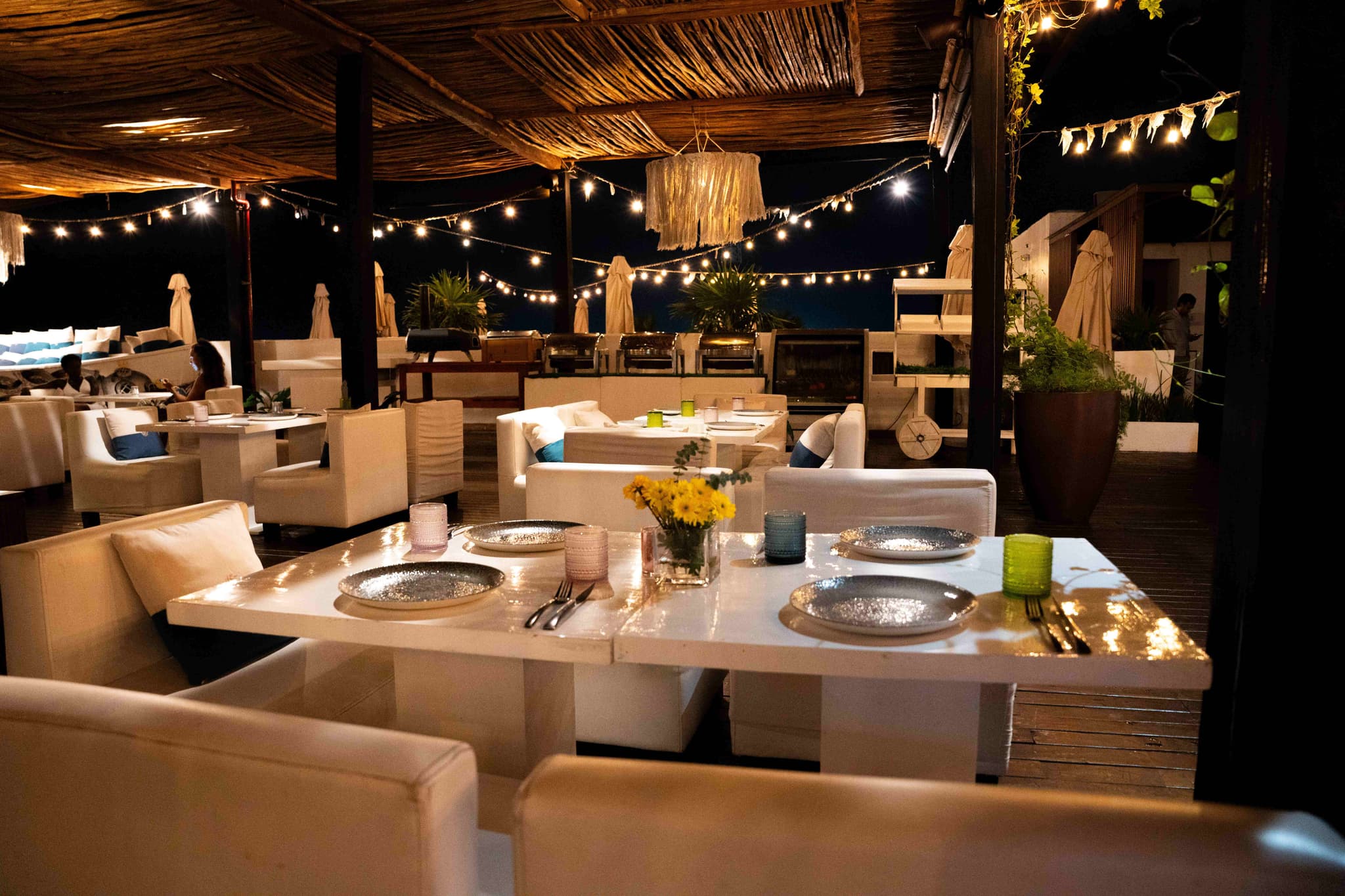 A set table at a beach restaurant under strings of lights