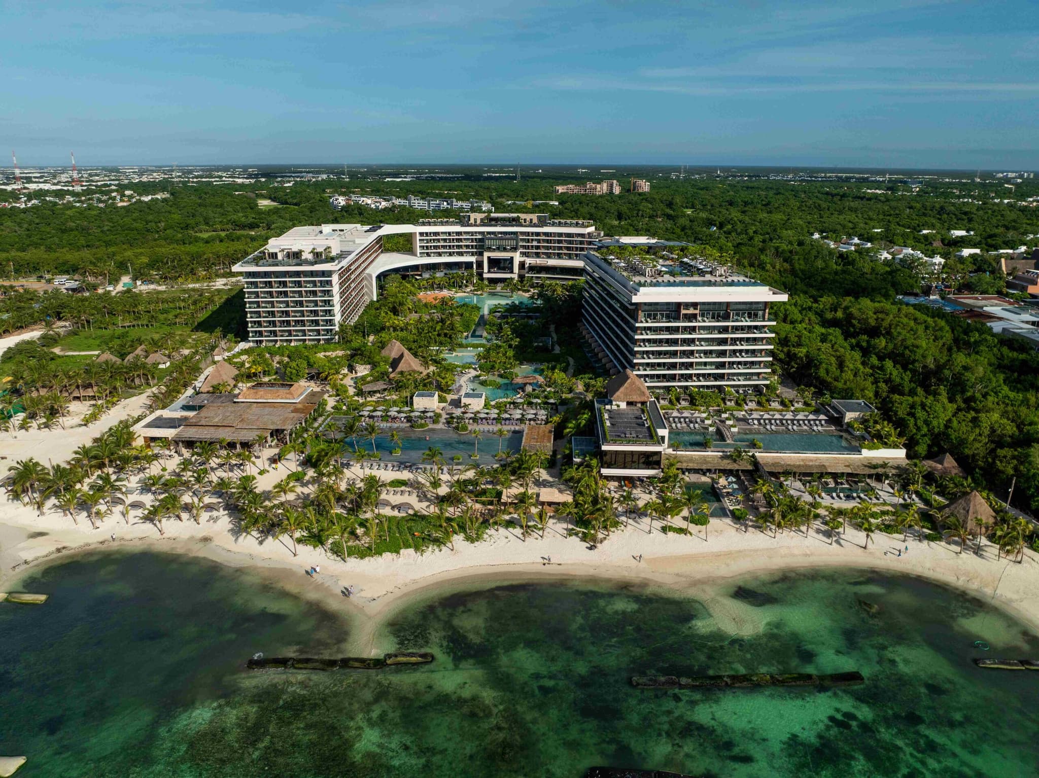 Aerial view of a curved resort between the jungle and the beach