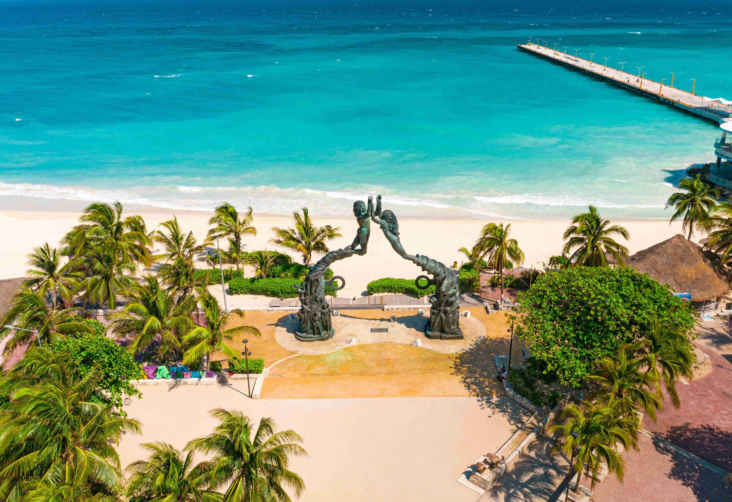 Aerial view of Parque Fundadores in Playa del Carmen, with the Portal Maya sculpture facing the beach and the pier