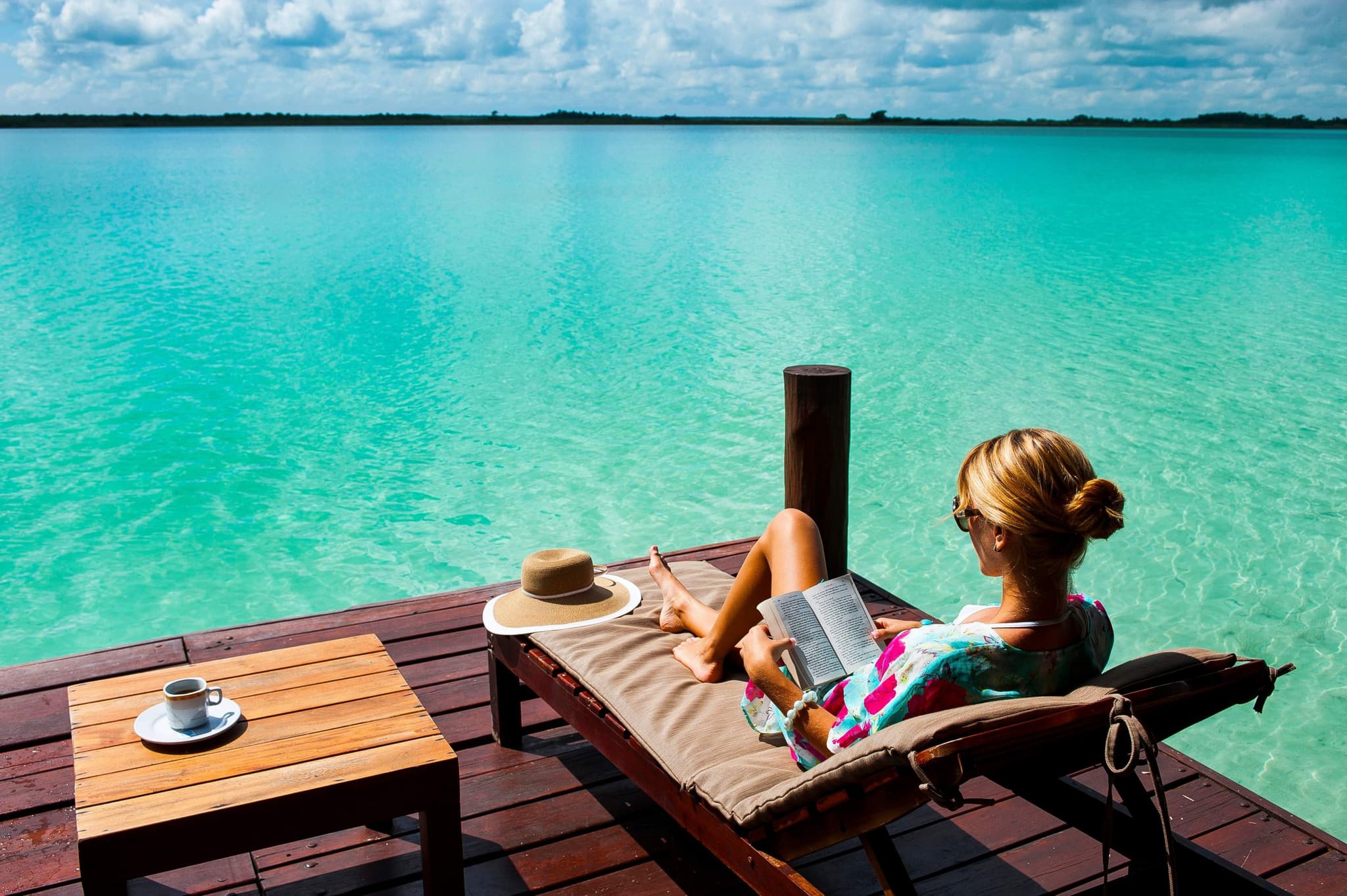 Woman reading on a wooden dock facing the lagoon