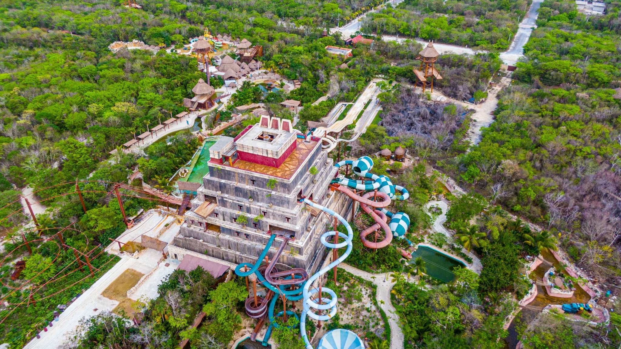 Aerial view of a water park with slides and a pyramid in the Mahahual jungle
